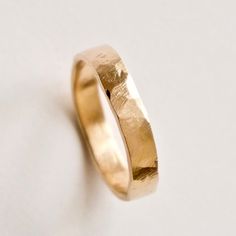 A hammered  gold ring which would be great as a unique wedding band. I start by making the band from 14 carat yellow gold and then hammer it by hand to create irregular indents and a rustic texture. I use a flat shape hammer that strikes the metal at slightly different angles and gives a really unique asymmetrical shape. The subtle ridged surface texture is also transferred onto the metal  which reminds me of naturally weathered stone. The photos shown here are 3mm and 4mm widths. They are 1.3-1 Hand Forged 14k Gold Engraved Wedding Ring, Minimalist Engraved Hammered Wedding Ring, Hammered 14k Gold Engraved Wedding Ring, Yellow Gold Hammered Wedding Ring, 14k Gold Hammered Wedding Rings, Hammered 14k Gold Wedding Rings, Hammered 14k Gold Wedding Band, Yellow Gold Engraved Wedding Ring With Hammered Detail, Heirloom Hammered Wedding Rings