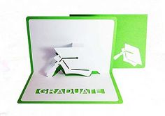 a green and white graduation card with the word graduate cut out