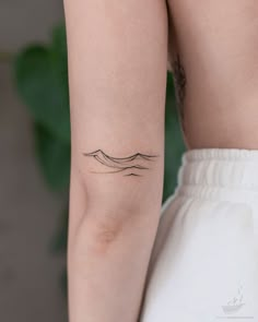 a woman's arm with a wave tattoo on the left side of her arm