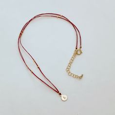 A very delicate necklace featuring double red thread strands, tiny golden nuggets on the sides and a round simple shape pendant.The pendant is custom stamped with the letter of your choice. Please, type the letter you want to be stamped on your pendant at check-out!∙ Only 1 letter permitted.∙ We use only capital letters.In many cultures, the color red is traditionally used as a symbol of protection, good luck, or blessing. In my native Argentina, red-is used to ward off evil spirits. Wear this n Golden Nugget, Thread Necklace, Red Thread, Round Necklace, Capital Letters, Neck Piece, Luck Charms, Evil Spirits, Simple Shapes