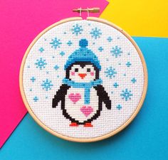 a cross stitch penguin with a blue hat and scarf