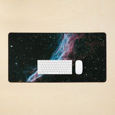 a computer mouse pad with a keyboard on it in front of a space themed background