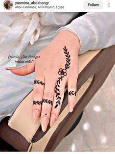 a woman's hand with a black flower tattoo on her left wrist and fingers