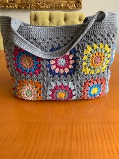 a crocheted purse sitting on top of a wooden table next to a painting