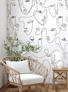 a chair and table in front of a wall with faces on it