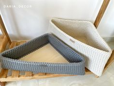 two crocheted baskets sitting on top of a wooden stand next to each other