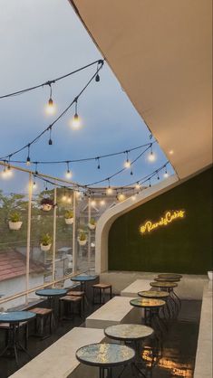 an outdoor restaurant with tables and chairs under string lights hanging from the ceiling above it