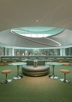 the circular seating area is surrounded by glass tables and stools, along with round lights