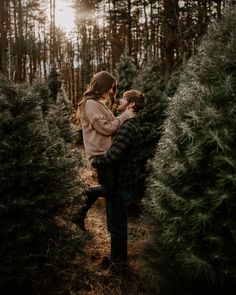 a couple cuddles in the middle of a christmas tree farm as the sun goes down