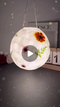 a hanging light with flowers painted on it