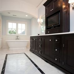 a large bathroom with black cabinets and white marble flooring is pictured in this image