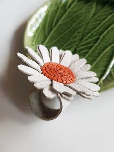 a white and orange flower sitting on top of a green leaf