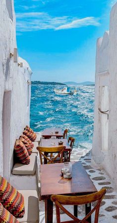 an outdoor seating area with tables and chairs overlooking the ocean in front of whitewashed buildings