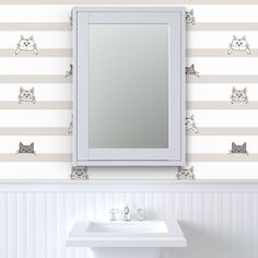 a white sink sitting under a bathroom mirror next to a wall with cats on it