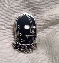 a black and white pin with a face on it