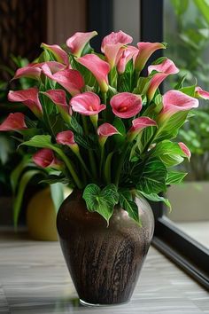 a vase filled with pink flowers sitting on top of a table next to a window