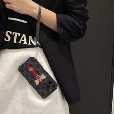 a woman holding a cell phone case with a gucci logo on it