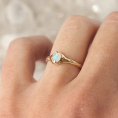 a woman's hand with a gold ring and an opal stone on it