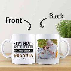 two coffee mugs sitting on top of a wooden table next to a potted plant