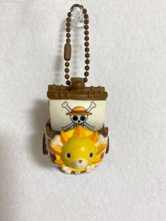 a small toy hanging on a wall with a chain around it's neck and an animal in the front