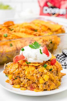 mexican casserole with sour cream on top and cornbread in the background, ready to be eaten