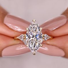 a woman's hand holding a ring with a large diamond in the center and two smaller diamonds on each side