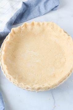 an uncooked pie sitting on top of a table next to a blue towel