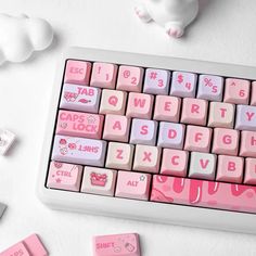 pink and white keyboard with hello kitty keycaps next to it on a table