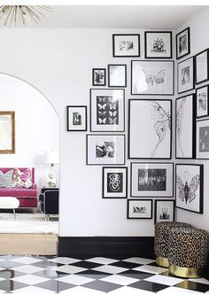 a living room with black and white checkered flooring, framed pictures on the wall