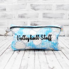 a blue and white cosmetic bag with volleyball balls on it, sitting on a wooden table