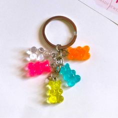 four gummy bears are sitting on top of a keychain and one is in the shape of a bear