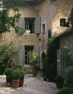 a stone house with green shutters and potted plants