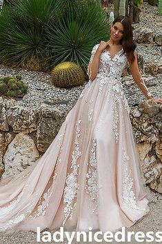 a woman standing in front of some rocks wearing a dress with white flowers on it