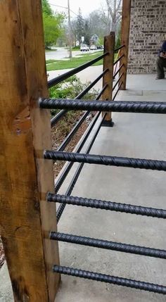 a man sitting on a bench next to a wooden pole with metal bars around it