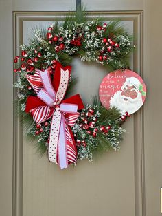 a christmas wreath hanging on the front door with a santa clause ornament next to it