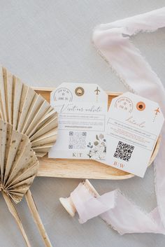 the wedding stationery is laid out in a wooden box with paper fans and ribbons