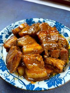 a blue and white plate topped with meat covered in sauce