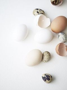 an assortment of different colored eggs on a white surface