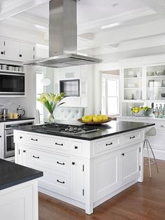 a large kitchen with white cabinets and black counter tops, an island in the middle