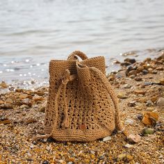 a crocheted bag sitting on top of a sandy beach next to the ocean