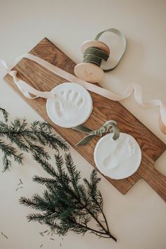 two white plates with handprints on them next to some ribbon and pine branches