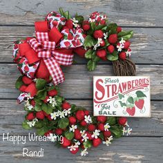 a wreath with strawberries and daisies on it is sitting next to a sign