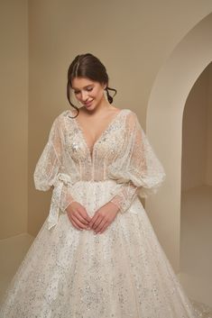 a woman in a white wedding dress standing next to a wall