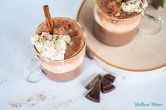 two mugs filled with hot chocolate and marshmallows on top of a plate