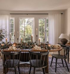 the dining room table is set with candles and greenery on it, along with four chairs