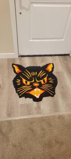 a door mat with an image of a cat's face on the floor in front of a door