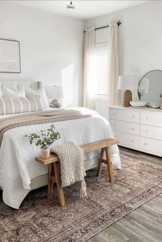 a bedroom with a large bed and white furniture