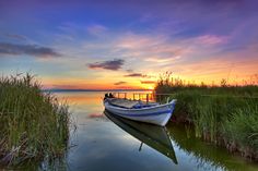 there is a boat that is sitting in the water at sunset or sunrise on the lake