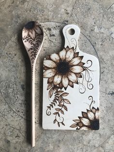 two spoons sitting next to each other on top of a stone surface with flowers painted on them