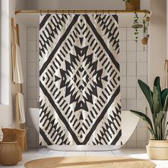 a black and white shower curtain hanging in a bathroom next to a potted plant